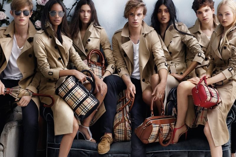 Models wearing Burberry outfits, showcasing luxury fashion with iconic trench coats and accessories.